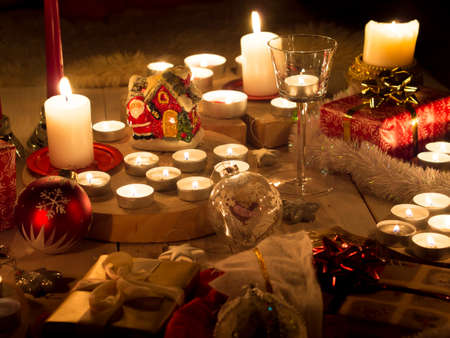 Christmas still life with candles of different size and shape, decorative round wood, souvenir Santa Claus clay house, gift boxes, christmas tree toy.の写真素材