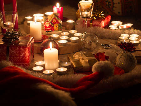 Christmas still life with candles of different size and shape, decorative round wood, souvenir Santa Claus clay house, gift boxes, christmas tree toy.の写真素材