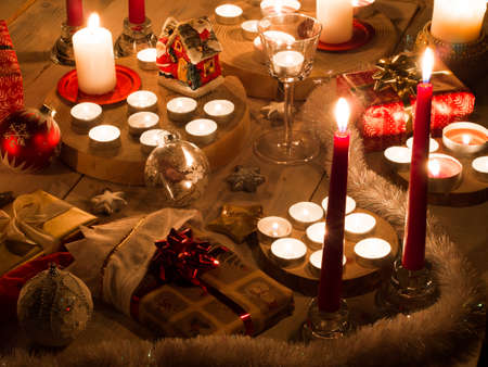 Christmas still life with candles of different size and shape, decorative round wood, souvenir Santa Claus clay house, gift boxes, christmas tree toy.の写真素材