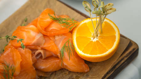 still life of salmon and cut in half orange on wood plateの写真素材