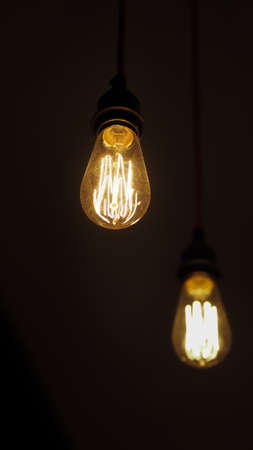 Two isolated vintage style glowing light bulbs one is unfocused closeup view with copy space の写真素材