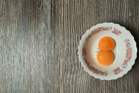 top view of raw egg yolk in a bowl on a wooden backgroundの写真素材
