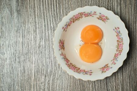 top view of raw egg yolk in a bowl on a wooden backgroundの写真素材