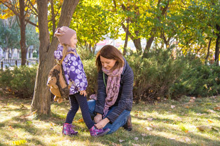 Young woman tying shoelaces young daughter..の写真素材