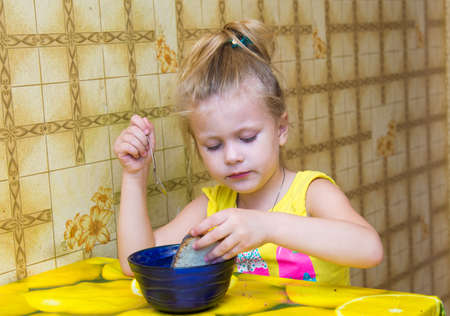 Little girl concentrating dunk the bread in a cupの写真素材