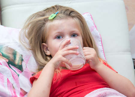 Little girl with a mug of milk in bedの写真素材