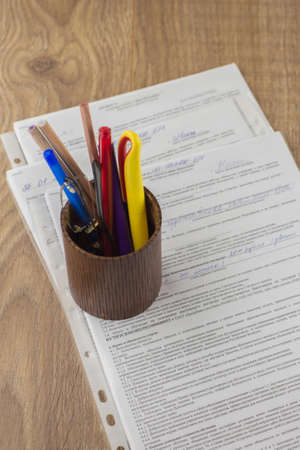 workplace of the businessman: some forms of contracts, filled and empty, and stationery in the pencil case, the space on topの写真素材