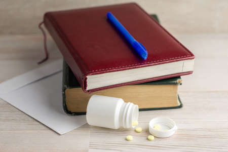 vigor at work: a pack of tablets of ephedrine. next lay on a wooden table an envelope, a notebook and blue penの写真素材