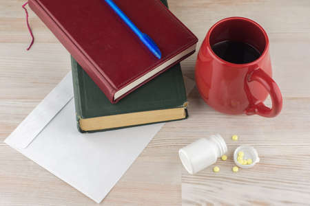 ensuring good employee: a pack of tablets of ephedrine, Cup of strong coffee. nearby are the envelope, a book, Notepad and blue pen, top viewの写真素材