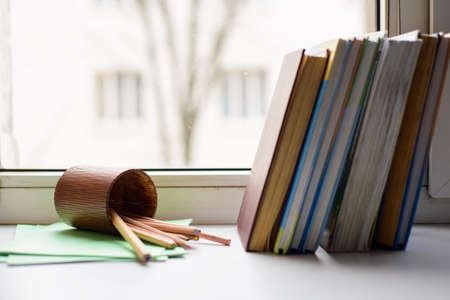 School and office supplies: colored Pencils, Pencils case and books on white window background