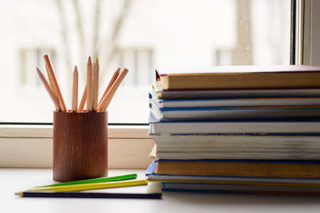 School and office supplies: colored Pencils, Pencils case and books on white window backgroundの写真素材
