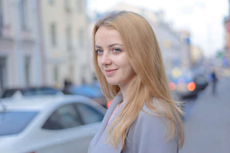 thoughtful stylish girl with red hair on a city streetの写真素材