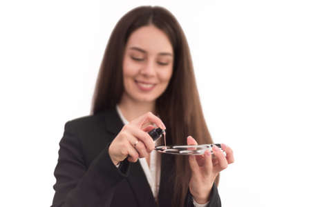 girl, make-up artist, with long dark hair in a business suit in a bright room squeezes foundation on a trayの写真素材