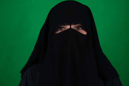 girl in muslim clothes on a green background, burqaの写真素材