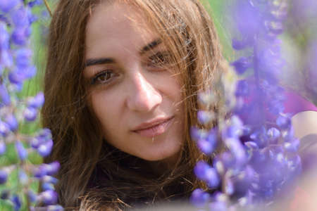 girl with long dark hair in a field with lupins