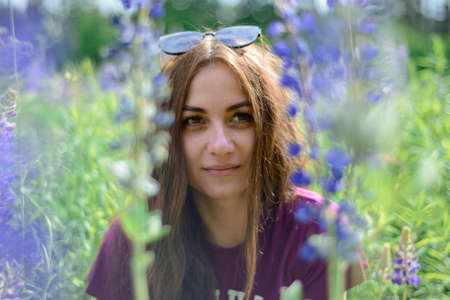 girl with long dark hair in a field with lupinsの写真素材