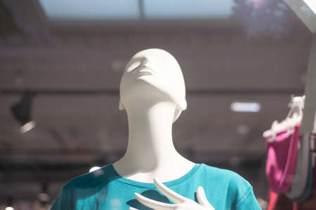 mannequins on a shop window in a blue t-shirt looks up