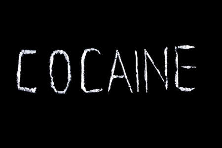 the word cocaine from white powder on a black backgroundの写真素材