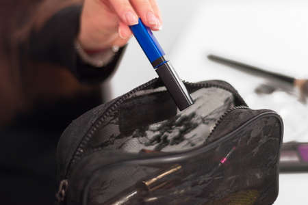 female hand pulls out a blue tube of black cosmetic bagの写真素材