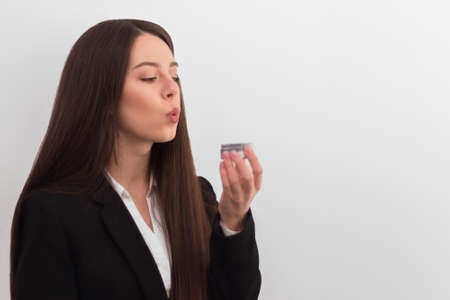 girl, makeup artist, with long dark hair in a business suit blows away the powder from the can on a...