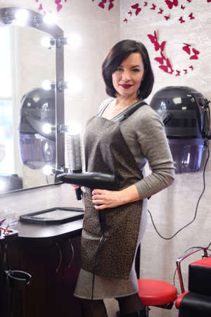 woman hairdresser with black hair with hairdryer and brushing in the hairdressing salonの写真素材