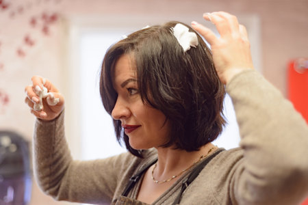 woman with black hair does her hair at the dressing table with a mirrorの写真素材