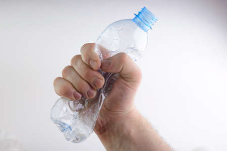 crumpled plastic bottle in hand on white backgroundの写真素材