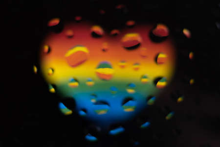 LGBT: a colorful heart in blurry focus under water drops on a black backgroundの写真素材