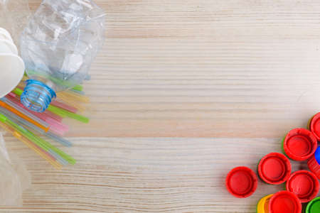 Plastic products on a wooden background: caps, tubes, cups, package, bottle