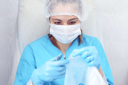 Girl in mask and medical gown with nail file and cuticle nippers in hands, salon worker, manicure...