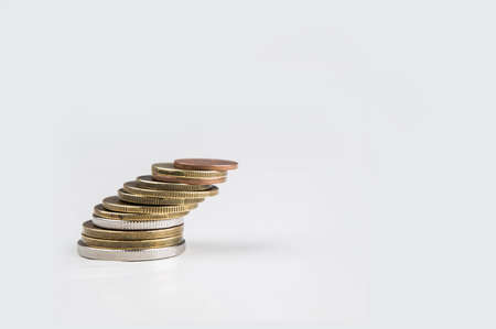 Precarious stack of various coins on white backgroundの写真素材