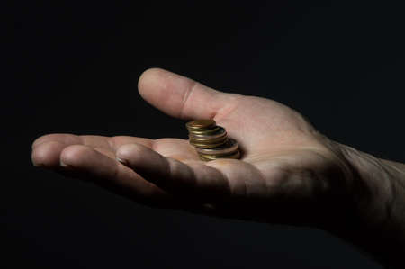 earning money: some coins on the palm of your hardworking hand on the dark backgroundの写真素材