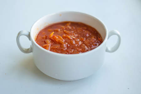red dish in a white bowl with two handles on a white background
