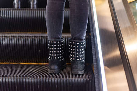 female legs in yellow pants and sneakers on the escalator stepの写真素材