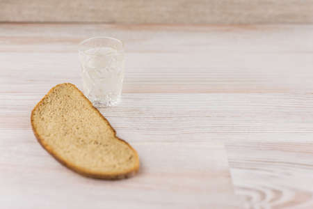the harmful addiction to alcohol, alcoholism: a Slice of black rye bread lying next to a glass of Russian vodka on wooden table, top view, space to the rightの写真素材