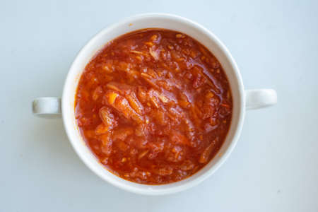 red dish in a white bowl with two handles on a white background