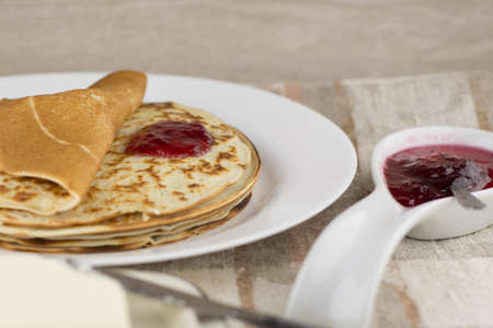 the celebration of carnival: fresh cooked real Russian pancakes made with yogurt, on a white plate, a little jam from the cranberriesの写真素材