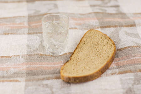 the harmful addiction to alcohol, alcoholism: a Slice of black rye bread lying next to a glass of...