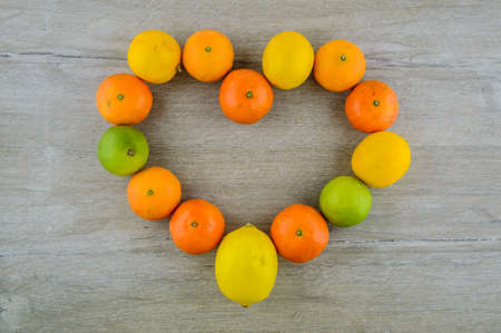Heart health: Useful citrus fruit: tangerines, lemons, limes laid out on the table in the shape of a heart, a source of pleasure. vitamins, mineralsの写真素材