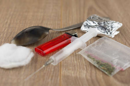 recruitment of occured injecting drug users: syringe, blackened spoon, cotton wool and a lighter lying next to a drug Packed in a foil and plastic package, short focusの写真素材