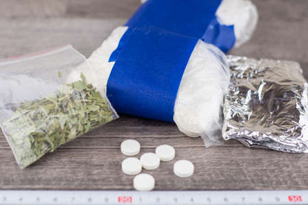 suspected drug trafficking, unknown pills, white powder in a transparent package and the foil, and like a "spice" blend, are on the table, a ruler for measurements posted belowの写真素材