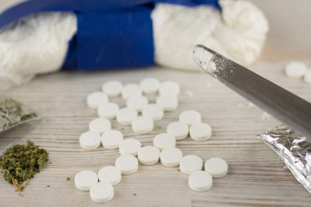 dangerous dependence - cocaine, heroin, spice, marijuana, and etc, the sign of death is depicted from tablets, top view, test powder on the tip of a knifeの写真素材