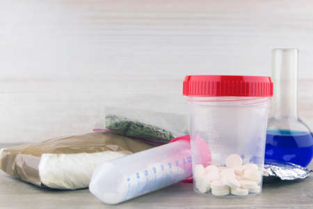 drug smuggling: 2 plastic container with unknown pills compared to other drugs, and the flask of solution for the test, short focusの写真素材