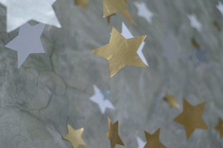 festive decoration: the falling paper shiny gold and silver stars on a background of gray stoneの写真素材