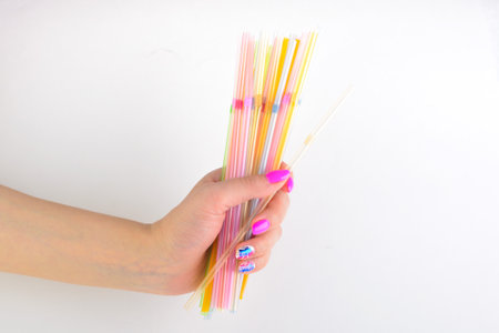 A bunch of multicolored plastic tubes in his hand on a white backgroundの写真素材