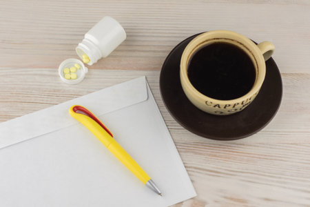 ensuring good employee: a pack of tablets of ephedrine, Cup of strong coffee. nearby lies on a wooden table an envelope and a ballpoint penの写真素材