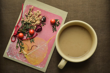 a Cup of fresh hot coffee and a few leaves, berries and flowers scattered on paper on the table