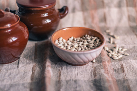 White beans in a clay deep plate on a linen tablecloth among clay pots, soft focusの写真素材