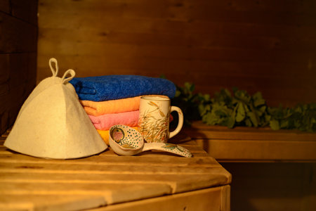 accessories for a sauna: a broom, a ladle, bath hats, colorful towels on a wooden shelfの写真素材