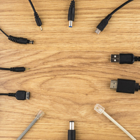 the background with the theme of technology: lots of different plugs and charger on a wooden table